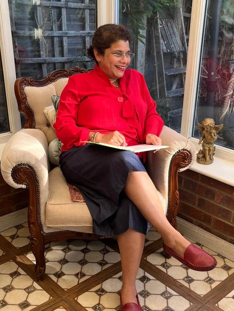 Charmaine laughing as she reads in her conservatory